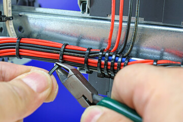Cutting plastic ties on insulated wires with a tool.