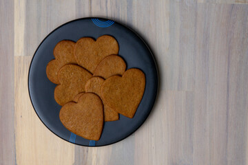 Heart-shaped cookies arranged on a black plate on a wooden surface ready for serving at a festive gathering