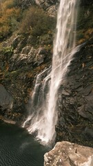 Waterfall cascading down rugged cliffs in autumn.
