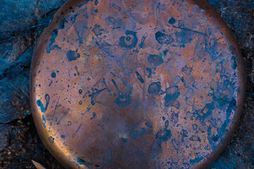 Circular Copper Plate on a Rough Surface in Deep Blue-Purple, and Red Tones. Design Background....