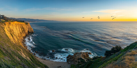 Naklejka premium A dramatic cliffside view overlooking the ocean at sunrise. Waves crash against the rocks below, and seagulls fly through the golden light. The rugged landscape conveys a sense of power and beauty.