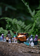 colorful gemstone crystals, witch copper cauldron and magic bottles in forest, natural background....