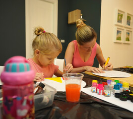 Fototapeta premium A mother and her young daughter engage in a colorful painting activity 