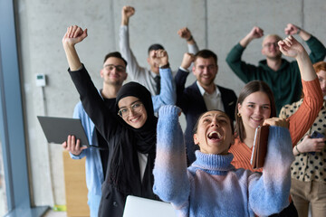 A diverse team of business professionals ecstatically celebrating their success in a modern office, expressing triumph and unity after achieving their goals