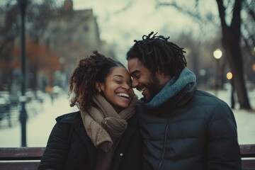 Fototapeta premium A joyful couple shares a tender moment in a winter park, surrounded by soft snow and muted landscape, showcasing love and warmth amidst the cold setting.
