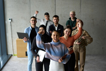 Fototapeta premium A diverse team of business professionals ecstatically celebrating their success in a modern office, expressing triumph and unity after achieving their goals