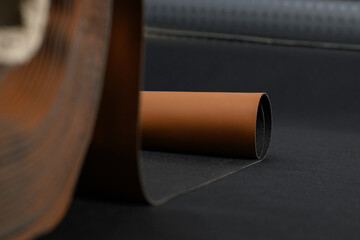 A close-up of a rolled-up industrial material, revealing a textured surface and a contrast between the dark and light tones. The image evokes a sense of strength and durability. 