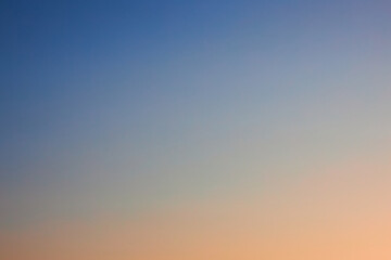 Gradient from blue to pink yellow. Photo of Cloudless clear sky at sunset, background. Natural gradient wallpaper. Peach fuzz color