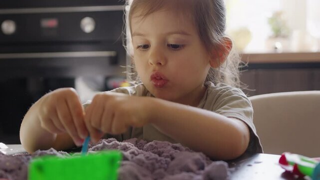 A Child Happily Engaged in Playing with Brightly Colored Kinetic Sand in the Kitchen Space at Home