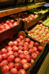 Red and green apples are neatly arranged in wooden crates on shelves at a supermarket, showcasing fresh, vibrant produce ready for sale.
