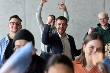 A diverse team of business professionals ecstatically celebrating their success in a modern office,...