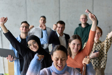 A diverse team of business professionals ecstatically celebrating their success in a modern office, expressing triumph and unity after achieving their goals