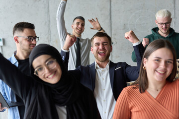 A diverse team of business professionals ecstatically celebrating their success in a modern office,...