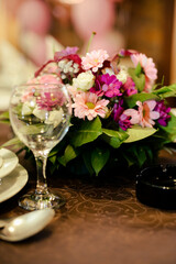 An empty wine glass on a served table next to which there is a bouquet of flowers as a decoration