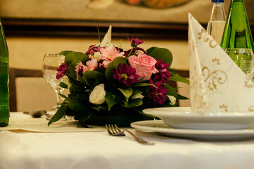 An empty wine glass on a served table next to which there is a bouquet of flowers as a decoration