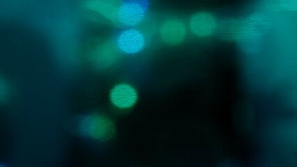 Blurred blue green lens flare motion studio lightning, texture reflection with bokeh effect on dark black background. Light leaks abstract background footage.