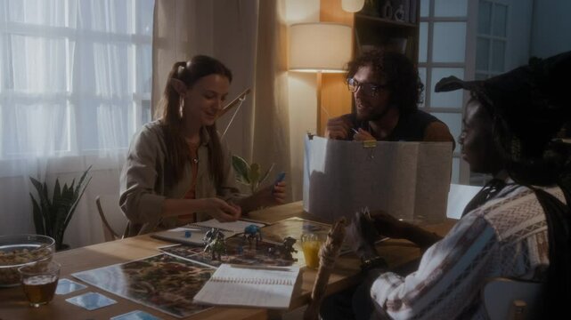 Three young male and female friends sitting at table enjoying role-playing fantasy tabletop game