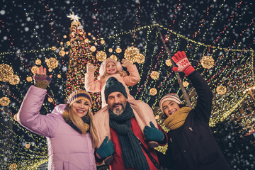 Naklejka premium Photo of cheerful school children husband wife cuddling walking x-mas park waving arms riding shoulders urban city market