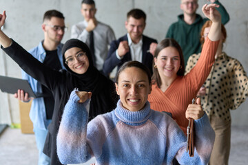 A diverse team of business professionals ecstatically celebrating their success in a modern office,...