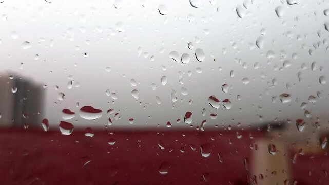 Blurry rain drops falling down over gloomy sky. Rain on window sky Drops.