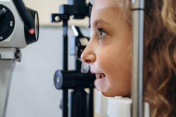 Close up view. Little girl is checking vision in the ophthalmologist cabinet