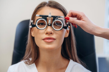 Pretty young woman is checking her vision in the ophthalmologist cabinet