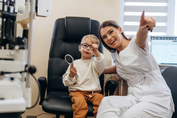 In the glasses. Little boy is having check up in the ophthalmologist cabinet