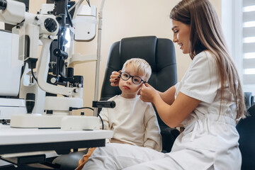 Fototapeta premium Trying new glasses. Little boy is having check up in the ophthalmologist cabinet