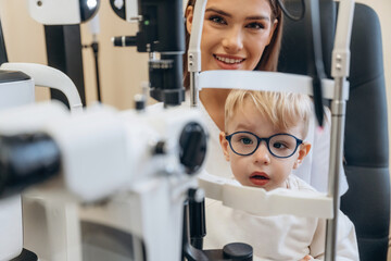 By the modern device. Little boy is having check up in the ophthalmologist cabinet