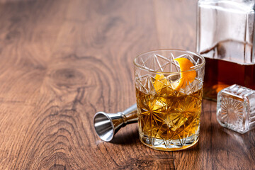 Old fashioned cocktail garnished with orange on wooden table. Copy space