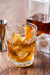 Old fashioned cocktail garnished with orange on wooden table