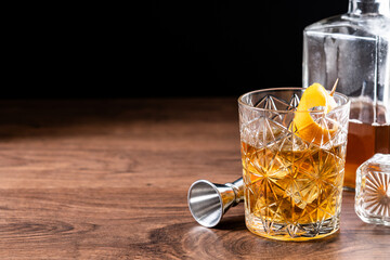 Old fashioned cocktail garnished with orange on wooden table. Copy space