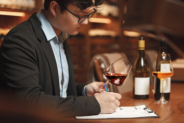 Man Writing Wine Descriptions Sitting at Cellar