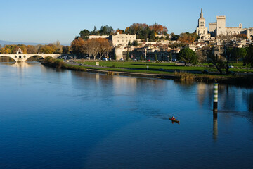 Fototapeta premium Scenic view of Avignon. The kayak is visible on the Rhône River in the foreground. On the left is the Saint-Bénézet Bridge (Pont d'Avignon). On the right is Palais des Papes (Palace of the Popes).