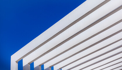 The fence on the sky background against the wall And abstract architecture contrasting with the blue sky With clear and beautiful light shadows Modern