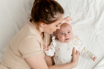 mom calms a crying newborn baby by putting him to sleep on a white bed at home