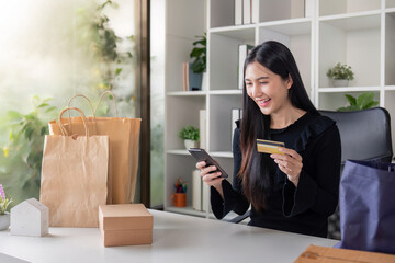 Happy woman using smartphone and credit card for online purchase