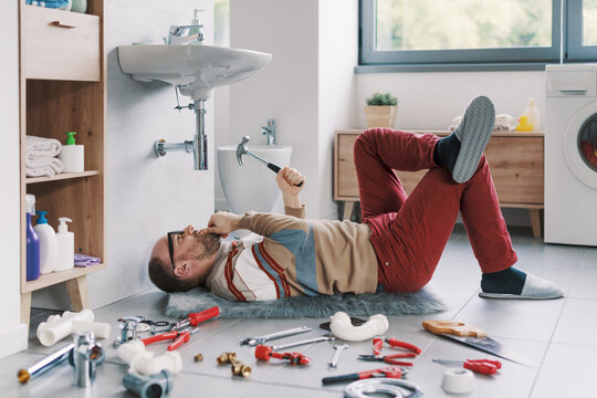 Unskilled confused man trying to repair his bathroom sink