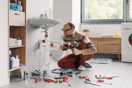 Inexpert man fixing his sink drain using adhesive tape