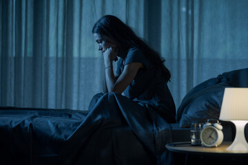Sad young woman awake in bed at night