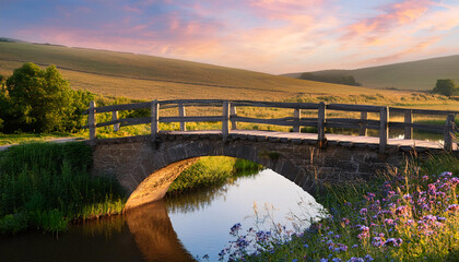 Obraz premium Rustic bridge spanning a calm river in a picturesque countryside during sunset with vibrant colors in the sky