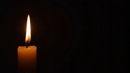 Single glowing candle in complete darkness