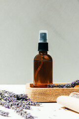 Set of natural cosmetics. Amber bottles with facial, bath liquid on a concrete background with lavender flowers. Front view