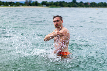 Junger sportlicher aktiver dynamischer Mann im Wasser beim Schwimmen und Fitness Training