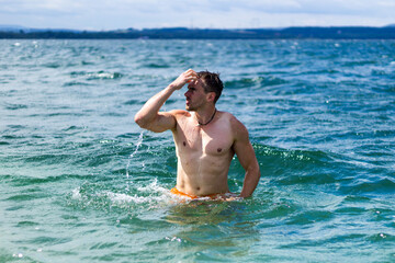 Junger sportlicher aktiver dynamischer Mann im Wasser beim Schwimmen und Fitness Training