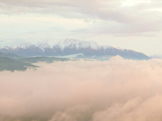 Drone view of  mountains at sunset. Beautiful pink clouds covered the earth. Evening landscape.