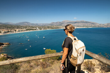 Girl with backpack looking at the sea