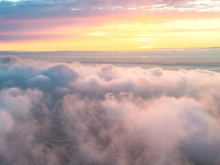 Drone view of clouds at sunset. Beautiful clouds covered the city. Bright evening golden, pink and...