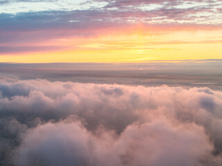 Drone view of clouds at sunset. Beautiful clouds covered the city. Bright evening golden, pink and...