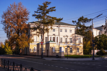 Historical building surrounded by autumn foliage on a clear day in a quiet neighborhood. Irkutsk city,